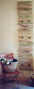 Wand-/Fensterdekoration aus verschiedenen Zweigen und Blättern, zum Beispiel Bambusstäbe und Strelizienblätter. Mit Holzperlen verfeinert.